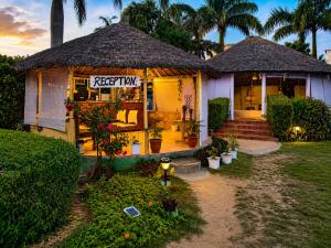 a small house with a thatched roof at Corbett Soho Resort in Haldwāni