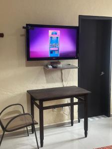 a tv on a wall with a table and a chair at Casa Victoria in Colima +5 photos