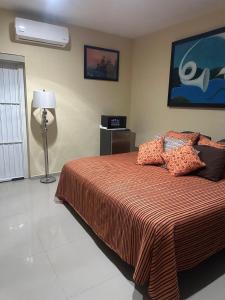 a bedroom with a bed with a orange bedspread at Casa Victoria in Colima