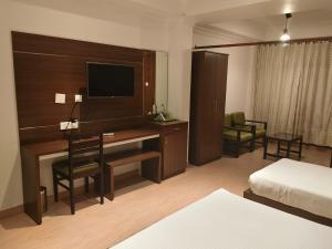a hotel room with a desk with a television and a bed at Matha Residency Munnar in Suryanelli