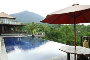 a table with an umbrella next to a swimming pool at Puri Karang Besakih in Menanga