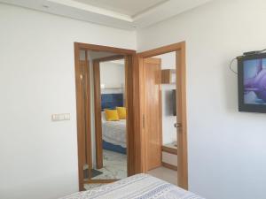 a bedroom with a bed and a tv on a wall at Appart Cosy in Fnidek