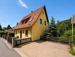 a yellow house with a brown roof and a fence at Haus Anni in Ebermannstadt