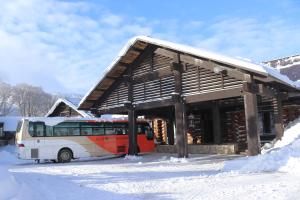 a bus parked in front of a building in the snow at Hakkoda Hotel in Aomori