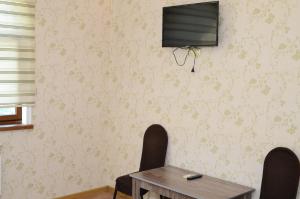 a dining room with a table and a television on a wall at Seki Qonaq Evi in Sheki
