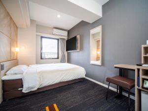 ein Schlafzimmer mit Bett, Schreibtisch und Fernseher in der Unterkunft Super Hotel Kobe in Kōbe
