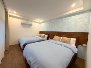 two beds in a hotel room with white sheets at Frania Sea Suites in san juan la union +3 photos