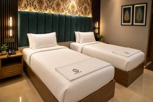 two beds in a room with a green headboard at The Park Lane Hotel in Krishnagiri