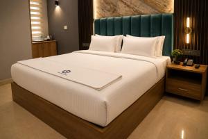 a large bed with white sheets and a green headboard at The Park Lane Hotel in Krishnagiri +1 photo