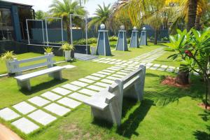 a park with two benches and a pathway with palm trees at The Park Lane Hotel in Krishnagiri