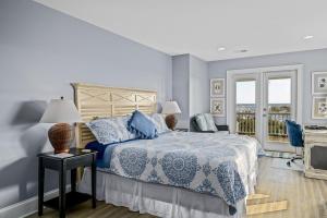 a bedroom with a blue and white bed and a balcony at Ohana in Holden Beach