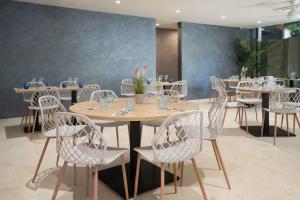 a dining room with tables and white chairs at Hotel Ciutat Martorell in Martorell