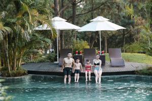 a family sitting in the swimming pool at a resort at AMAYA HOME - Lodge, Spa & Restaurant Sóc Sơn in Sóc Sơn