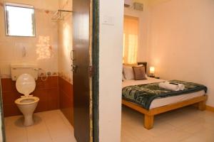 a bathroom with a bed and a toilet in a room at Green Woods Cottage by JN in Mahabaleshwar