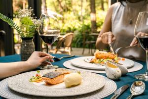 a table with plates of food and glasses of wine at AMAYA HOME - Lodge, Spa & Restaurant Sóc Sơn in Sóc Sơn