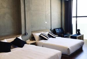 a hotel room with two beds and a chair at 境域Loft自助民宿 in Kaohsiung