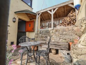 a patio with a table and chairs and a stone wall at Sammy Hakes Cottage in Watchet