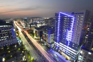 Haeden Hotel High End Suwon في سوون: المدينة مضاءة ليلا بالمباني والزحمة