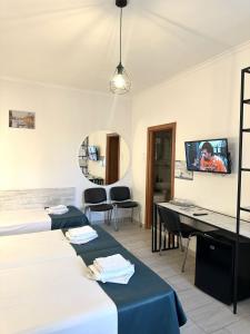 ein Zimmer mit drei Betten und einem Schreibtisch und einem Fernseher in der Unterkunft Pension Recidency in Oradea