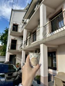 Eine Person, die vor einem Gebäude eine Tasse hält. in der Unterkunft Pension Recidency in Oradea