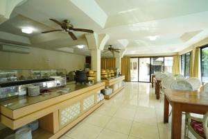a large kitchen with tables and chairs and a ceiling fan at Hotel Grand Rosela in Yogyakarta