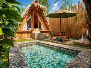 a small pool with a table and an umbrella at New Dgyp Ciater Resort in Ciater