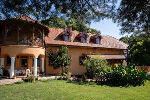 a large yellow house with a balcony on a yard at Hárs Fogadó in Ötvös