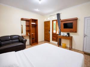 a bedroom with a bed and a couch and a television at New Dgyp Ciater Resort in Ciater