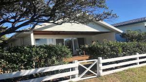 a white fence in front of a white house at 18 On Main in Wooli