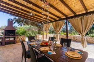 an outdoor dining table with chairs and a fireplace at Casina dei Capperi by Vivimy in Torre Pali
