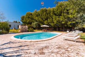a swimming pool in a yard with benches and trees at Casina dei Capperi by Vivimy in Torre Pali