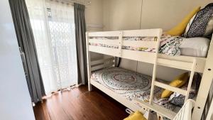 a small room with two bunk beds in it at Frangipani Cottage in Wooli