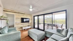 a living room with a couch and chairs and a television at JJ s Holiday House in Wooli