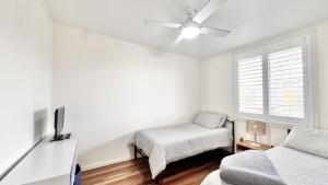 a white bedroom with a bed and a window at JJ s Holiday House in Wooli +6 photos