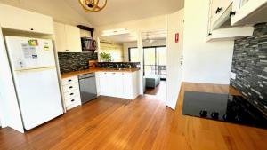 a kitchen with a white refrigerator and a wooden floor at JJ s Holiday House in Wooli