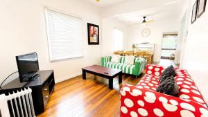 a living room with a red and white couch and a tv at Teke Cottage in Wooli