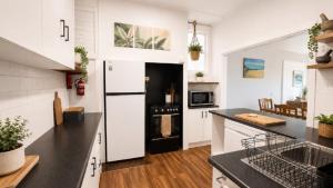 a kitchen with white cabinets and a black and white refrigerator at Surfside in Wooli