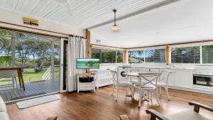 a kitchen with a table and chairs and a television at Tullenderly in Wooli