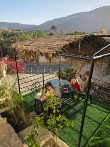 a group of people sitting in chairs under a thatch roof at Wadi Bani Khalid Guest house in Dawwah