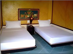 two beds with white sheets in a room at Pangsarapee Resort in Ban Bo Nam Khao