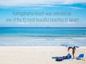a couple standing on the beach under an umbrella at Villa Yumigahama in Minamiizu