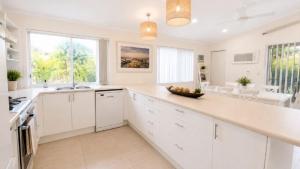a kitchen with white cabinets and a counter top at Sandy Feet in Wooli