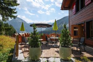 a patio with a table and chairs and an umbrella at Hotel Sonnenhalde, Arosa in Arosa