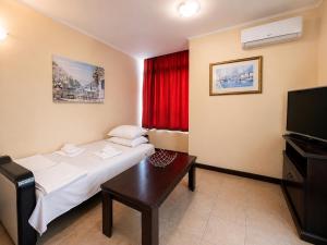 a hotel room with a bed and a television at Красавиците тъмнокоси Sunset Family in Pomorie