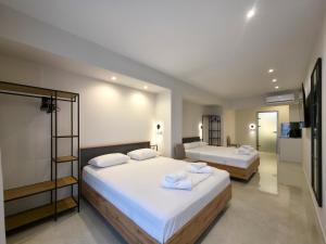 a bedroom with two beds with white sheets at Lucia Hotel Paralia in Paralia Katerinis