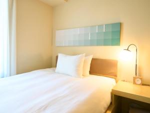 a bedroom with a white bed and a desk with a lamp at Hotel Resol Ikebukuro in Tokyo