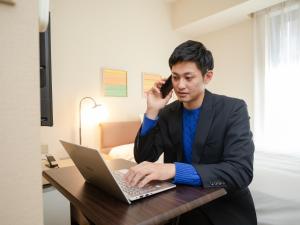 a man in a suit sitting at a table with a laptop at Hotel Resol Ikebukuro in Tokyo