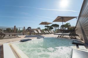 a swimming pool with chairs and umbrellas on a patio at Park Gallanti in Lido di Pomposa