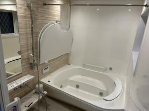 a bathroom with a bath tub with a mirror at Kibe House in Kunisaki