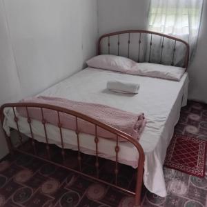 a bed with a metal frame and white sheets at Pelly Homestay Adventure in Taveuni